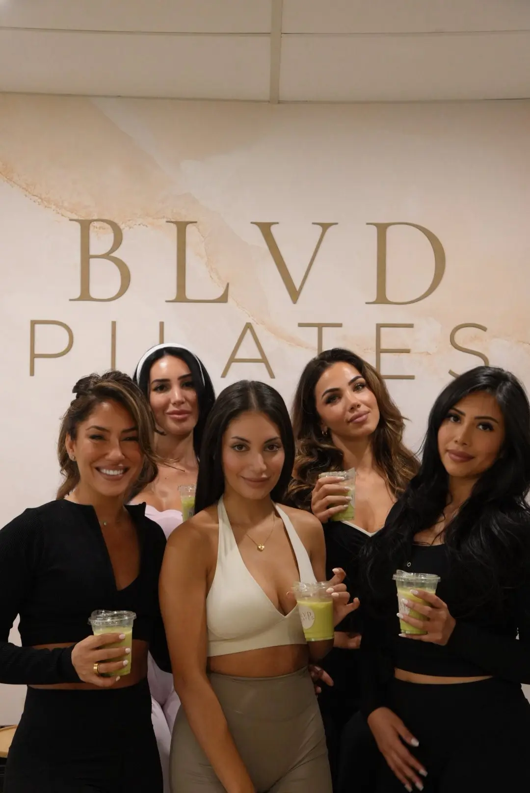 L'équipe d'instructrices BLVD Pilates devant le logo du studio