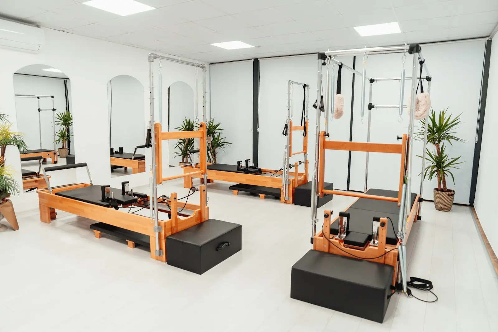 Studio de Pilates lumineux avec Reformers, tours en bois et plantes