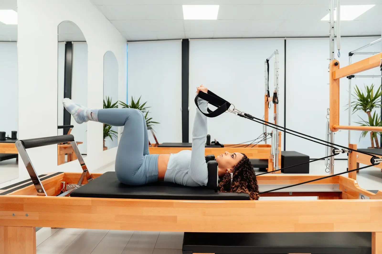 Femme allongée sur un Reformer, jambes tendues dans les sangles