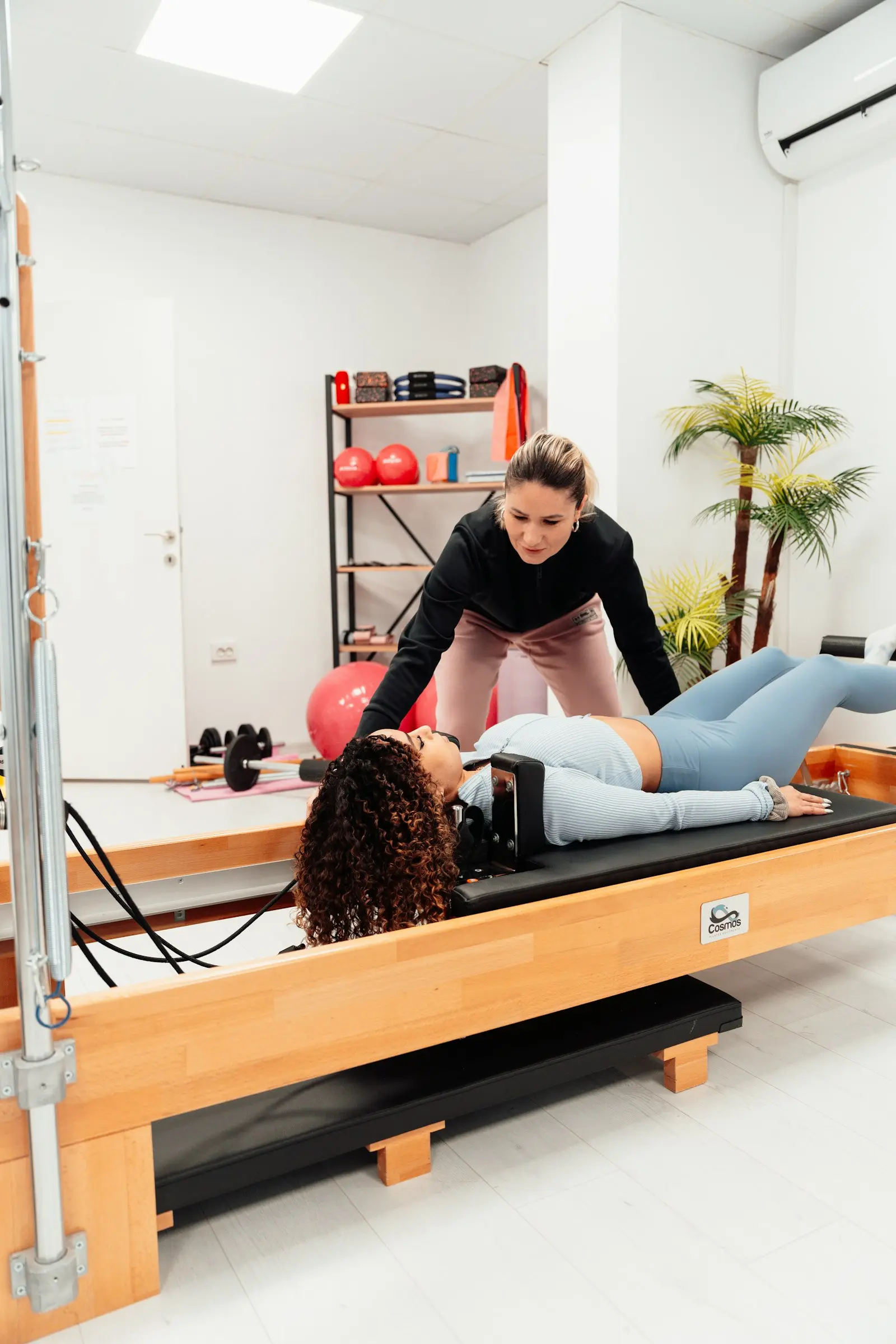 Instructrice qui guide une cliente allongée sur un Reformer