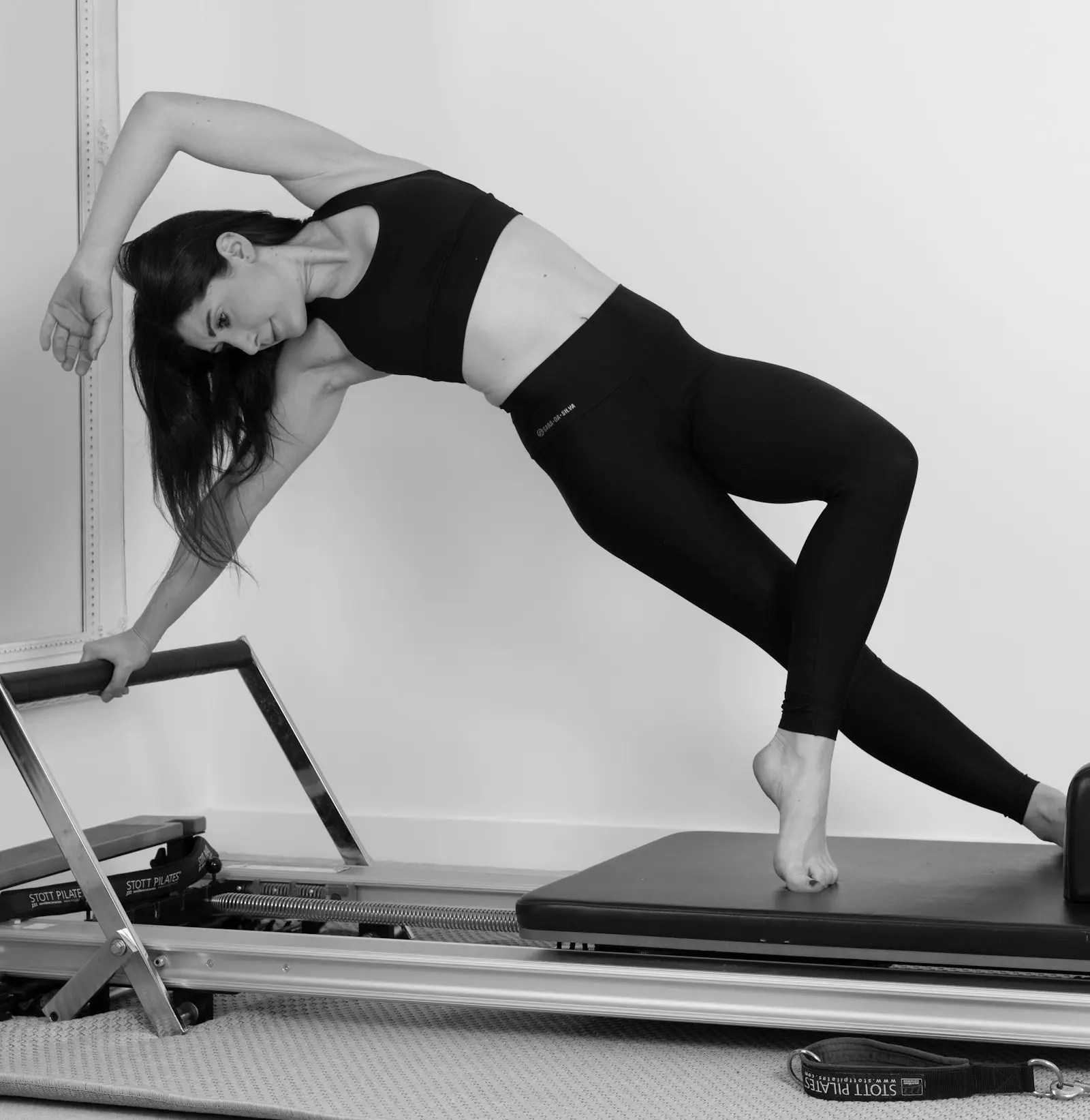 Femme en fente latérale sur un Reformer, en noir et blanc