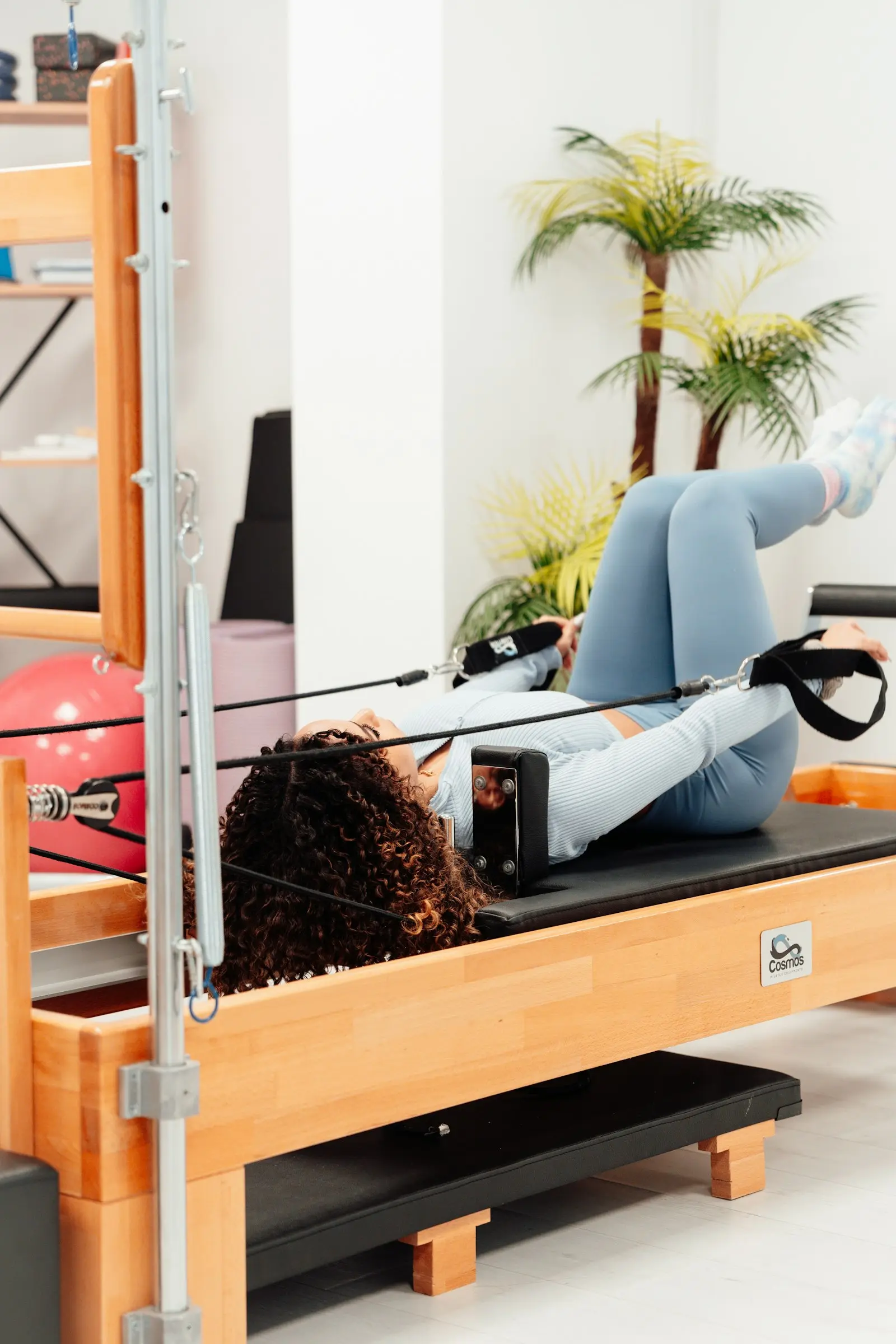 Femme allongée sur un Reformer, jambes levées dans les sangles