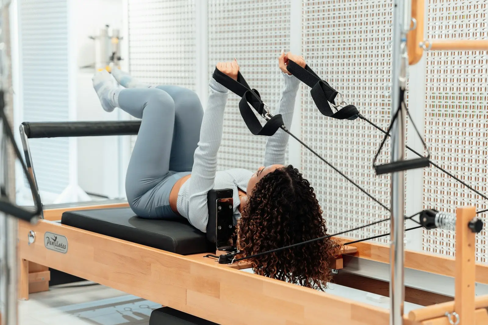 Femme allongée sur un Reformer, jambes dans les sangles