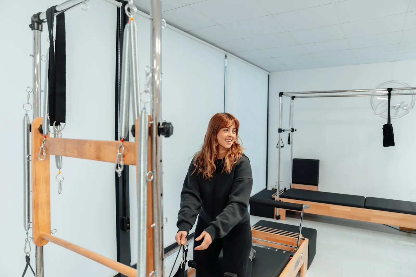 Femme qui ajuste un Reformer dans un studio lumineux
