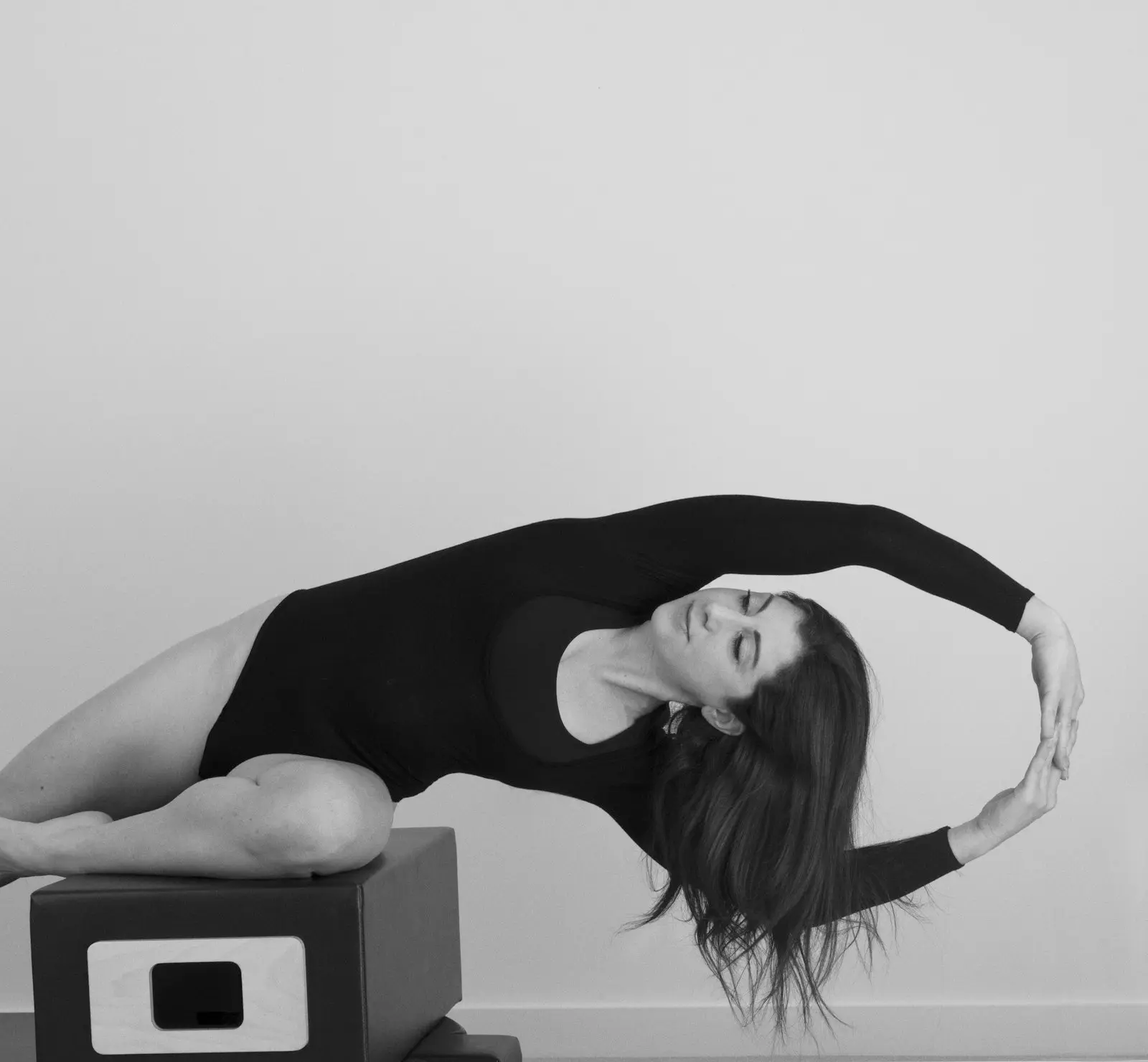 Femme en extension latérale sur un baril de Pilates, en noir et blanc