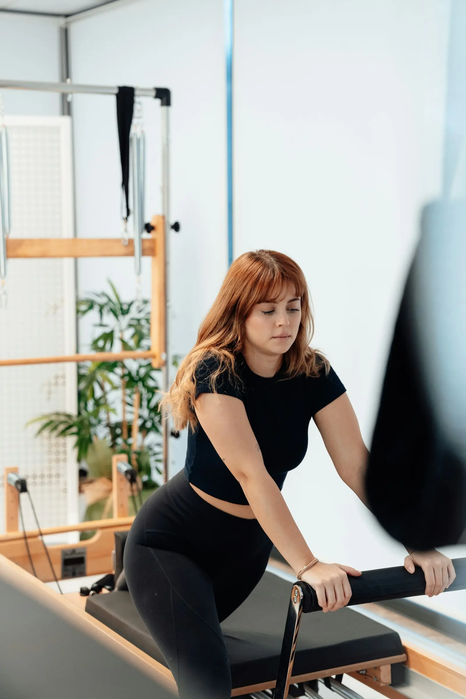 Femme aux cheveux roux qui tient la barre d’un Reformer