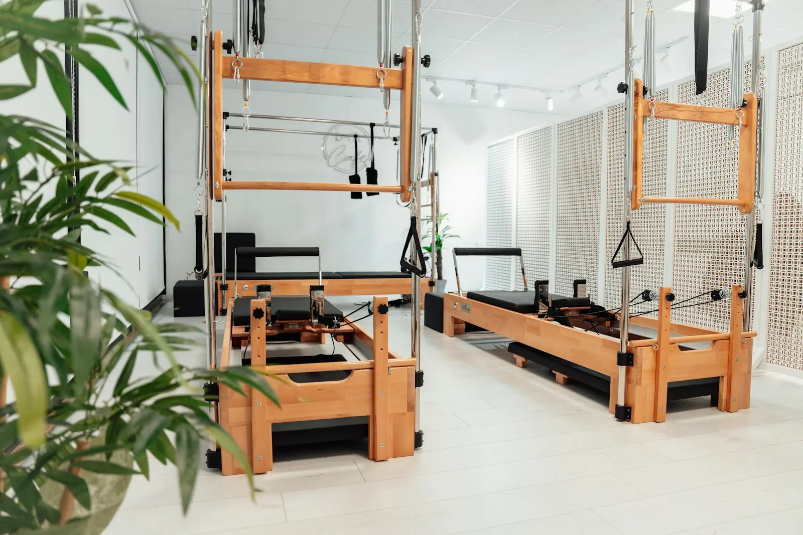 Studio de Pilates lumineux avec tours en bois, Reformers et plantes