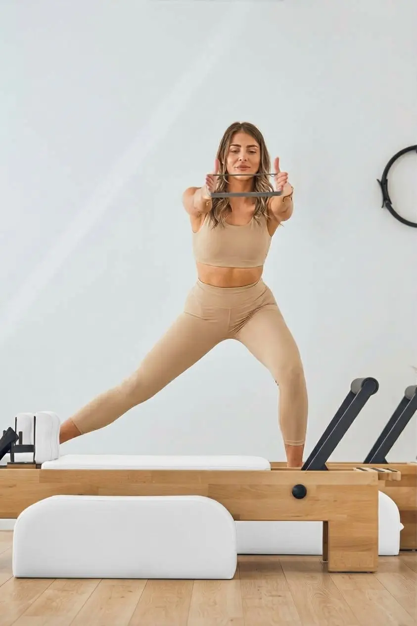 Femme qui fait un exercice debout sur un Reformer avec un cercle de Pilates